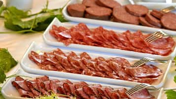 Una mesa con diversos alimentos, como carnes en rodajas, verduras y guarniciones.
