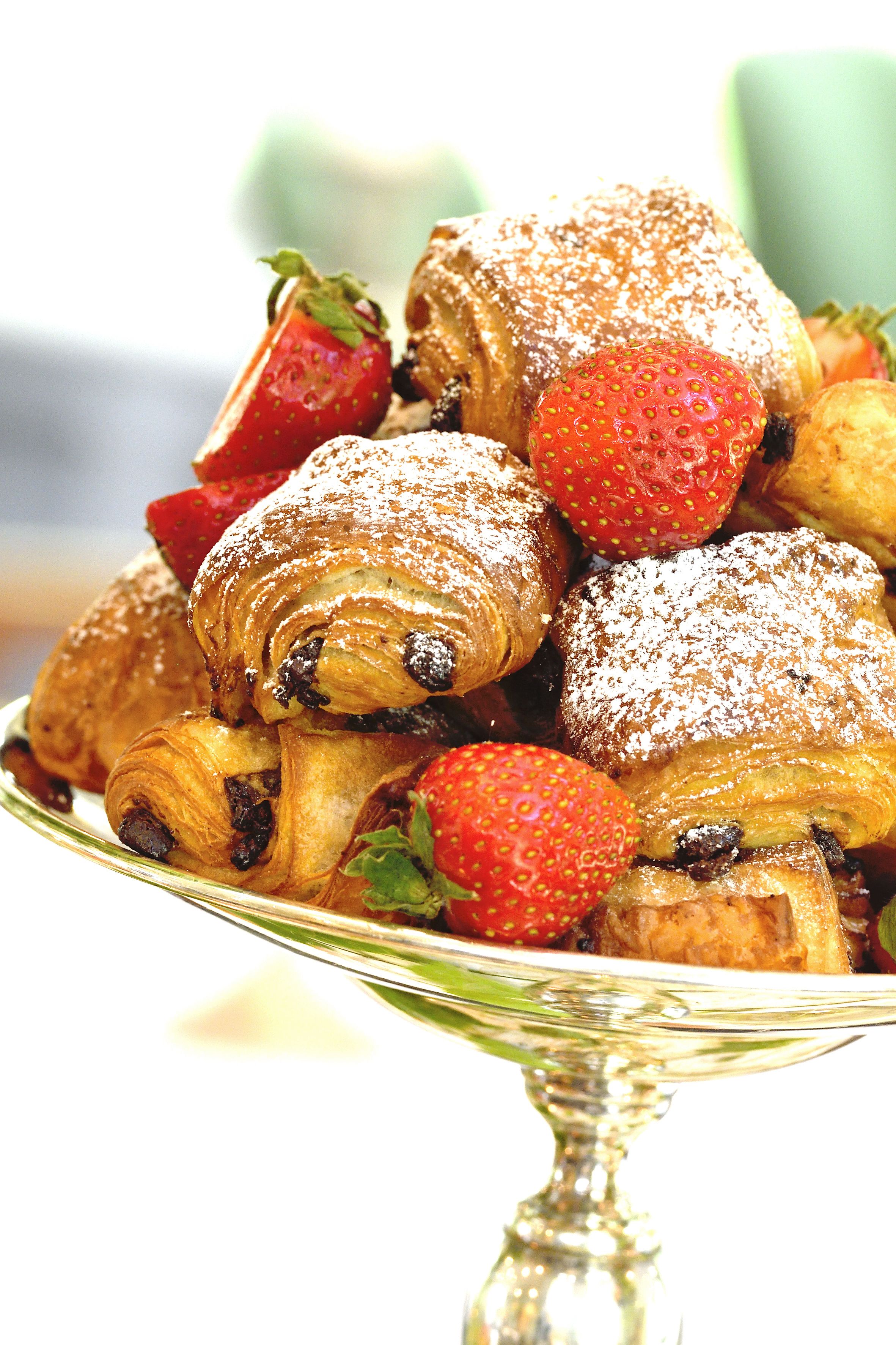 A plate of pastries with strawberries on a reflective surface.