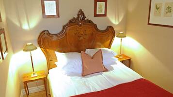 A neatly made bed with a wooden headboard, two bedside lamps, and a red throw blanket.