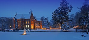 A large, historic building with a snow-covered landscape and a fountain in the foreground. - Thorskogs Slott (Västerlanda)