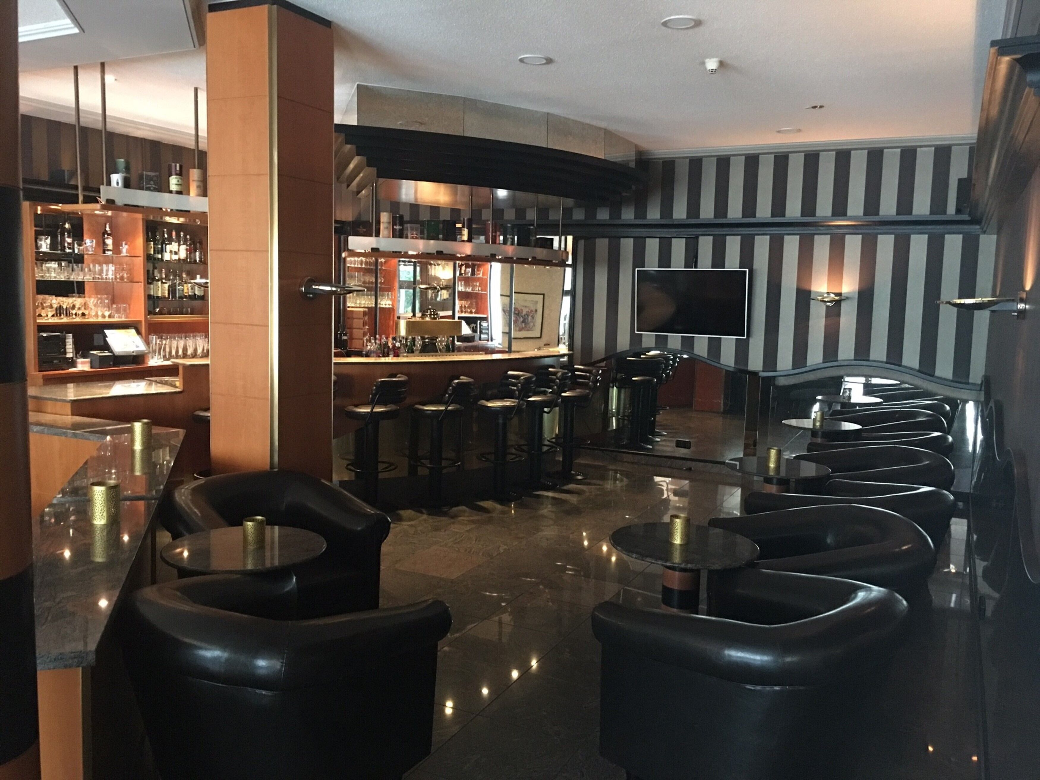 A bar area with a counter, stools, and a television screen.