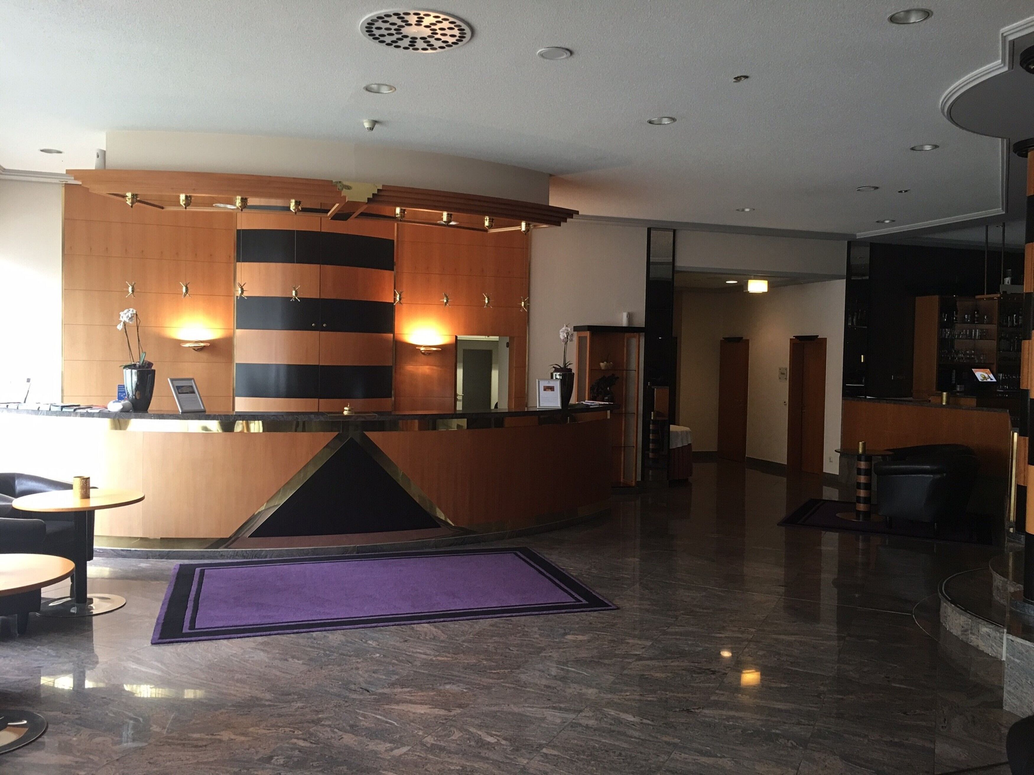 A modern reception area with a curved desk, wooden paneling, and a purple rug.