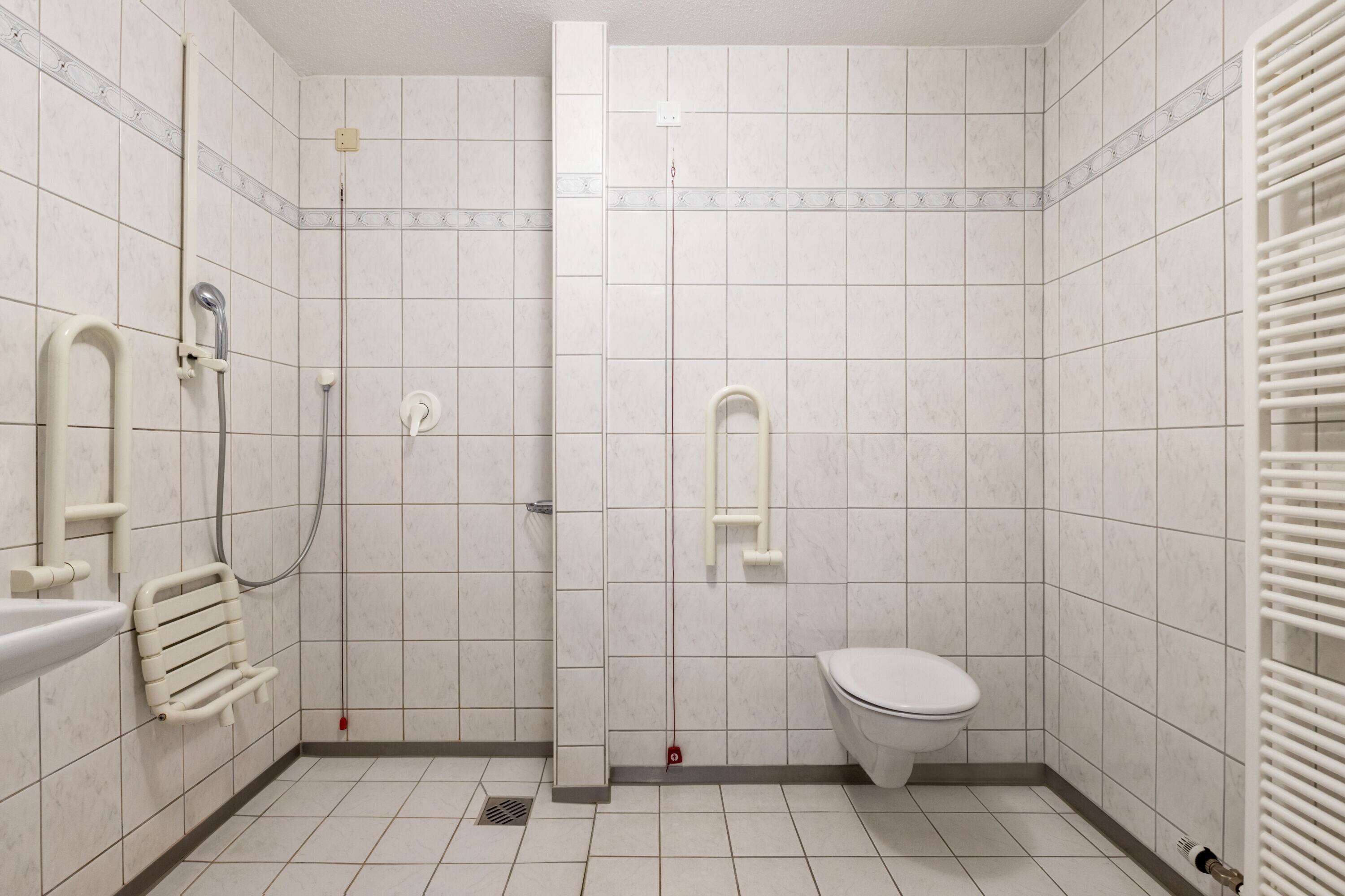 A small, tiled bathroom with a toilet, a shower, and a sink.