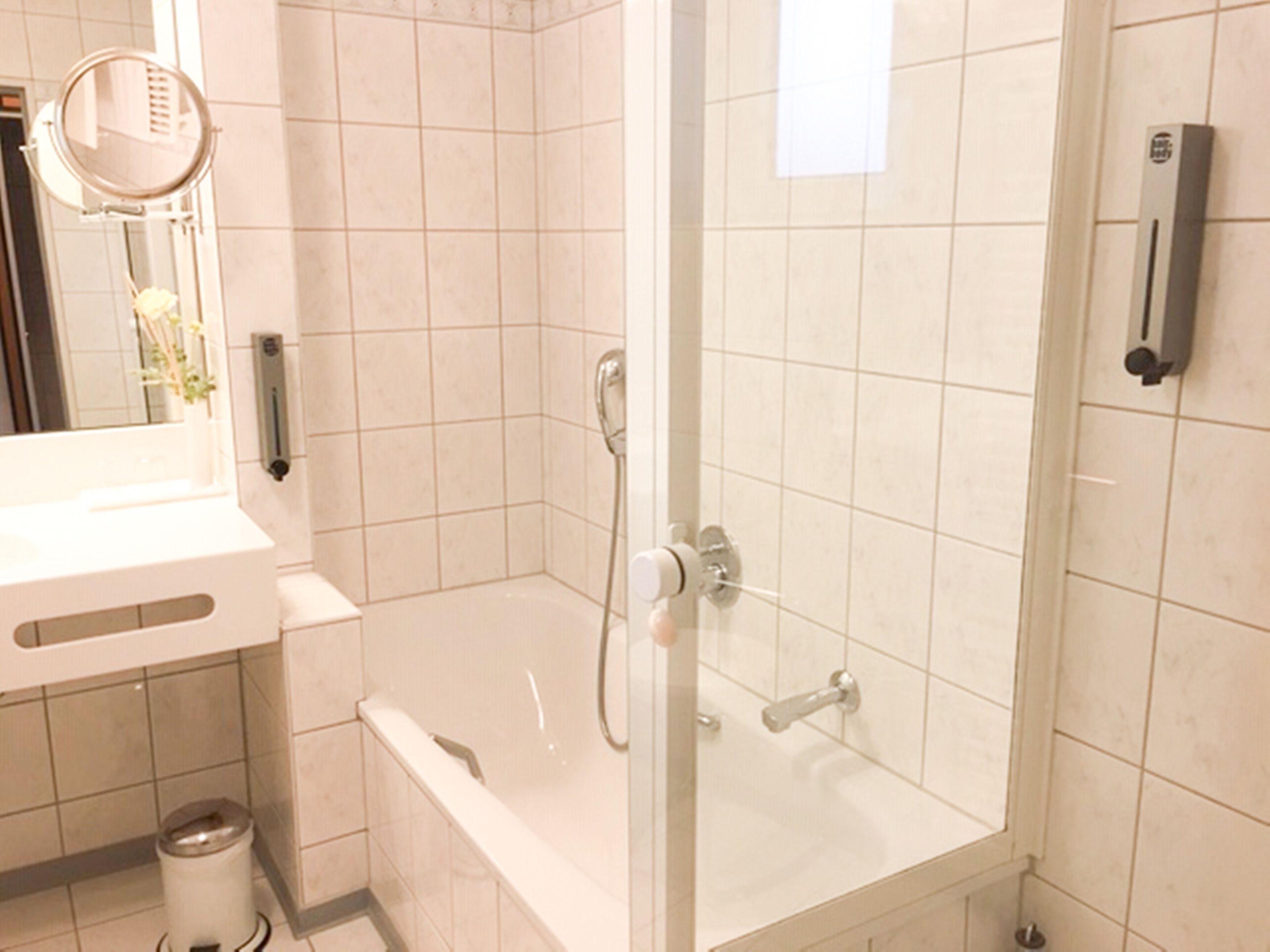Une salle de bain avec une baignoire, une douche et un miroir.
