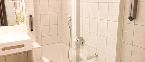 Une salle de bain avec une baignoire, une douche et un miroir.