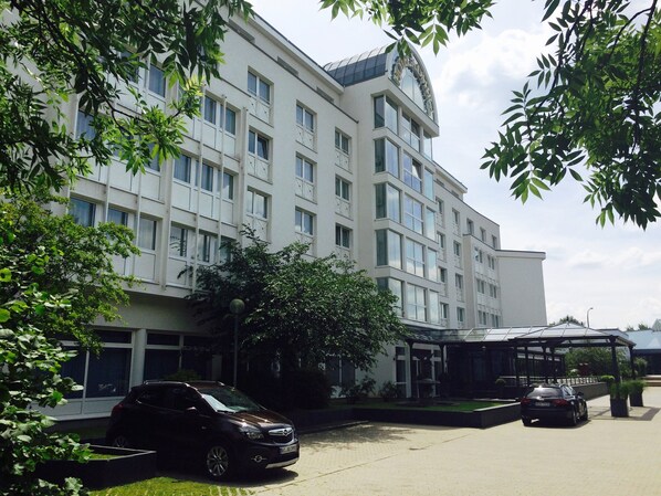 Un hotel de varios pisos con un diseño arquitectónico moderno, que destaca por una fachada curva de vidrio y un área de entrada cubierta.