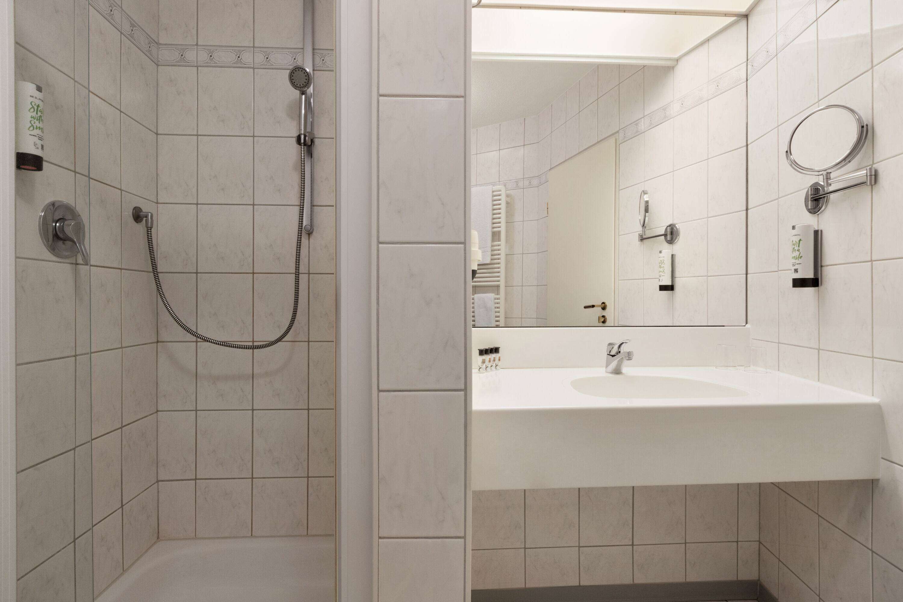 A bathroom with a shower, sink, and mirror.