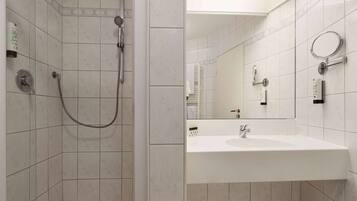 A bathroom with a shower, sink, and mirror.