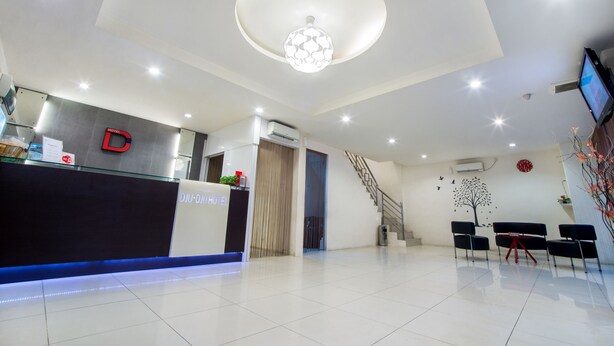 A hotel reception area with a modern design, including a reception desk, a staircase, and a seating area. - Dju Dju Hotel (Batam)