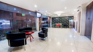 A modern hotel lobby with a reception desk, seating area, and a large window overlooking the street. - Dju Dju Hotel (Batam)