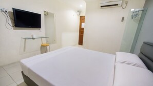 A bedroom with a bed, a TV mounted on the wall, a glass shelf, and an air conditioning unit. - Dju Dju Hotel (Batam)