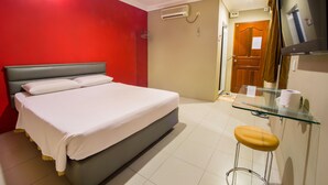 A hotel room with a bed, a glass table with a stool, a TV, and a door. - Dju Dju Hotel (Batam)