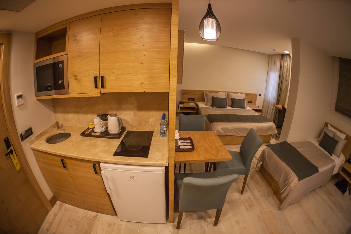 Habitación de hotel compacta con kitchenette, zona de comedor y dos camas individuales.