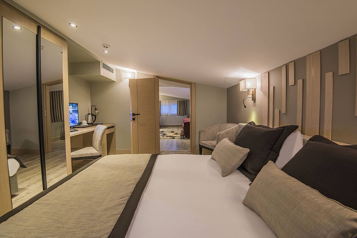 Una habitación de hotel con una cama grande, un escritorio, una silla y un espejo.