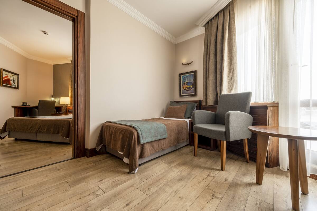 Habitación de hotel con cama, una silla, una mesa y un cuadro en la pared.