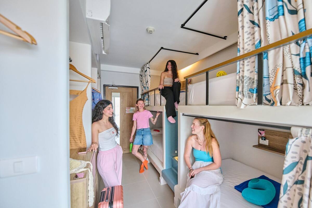A dormitory room with bunk beds, a small kitchenette, and a bathroom.