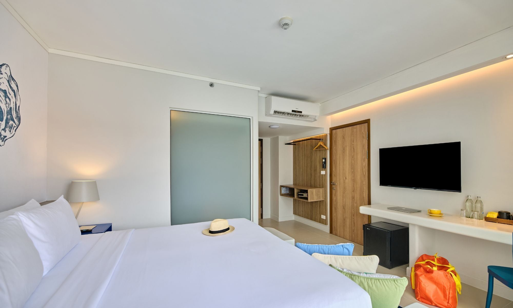 A modern hotel room with a bed, a TV, a desk, and a wardrobe.