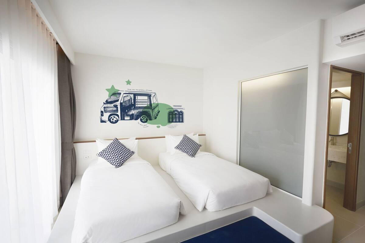 A hotel room with two beds, a large mirror, and a wall decal of a truck.