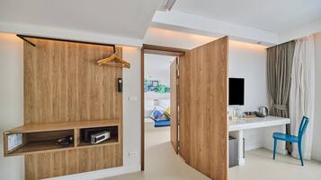 A modern hotel room with a wooden wardrobe, a desk with a chair, a TV, and a view of the outside.