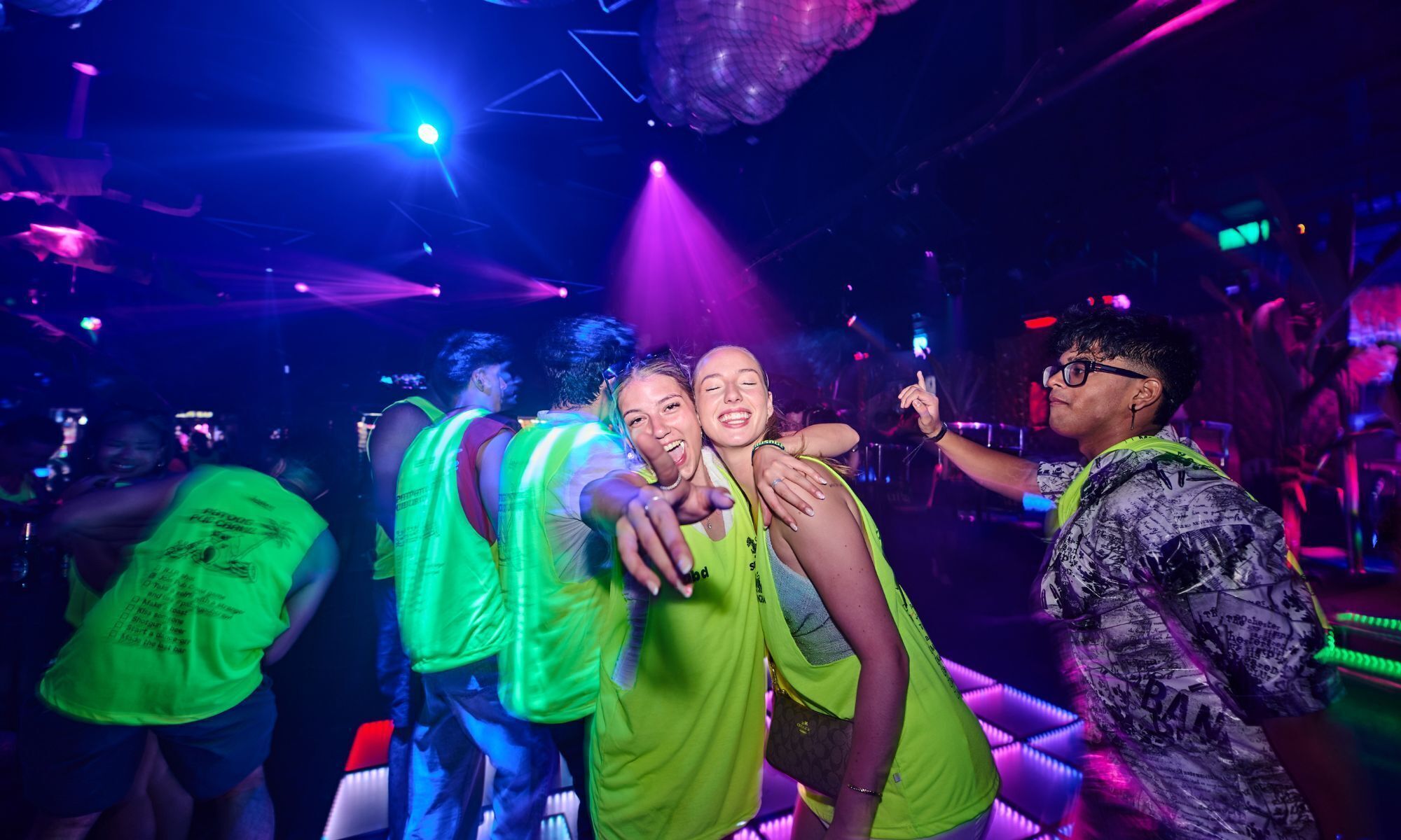 A group of people in a dimly lit room with colorful lighting.