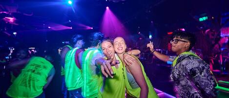A group of people in a dimly lit room with colorful lighting.