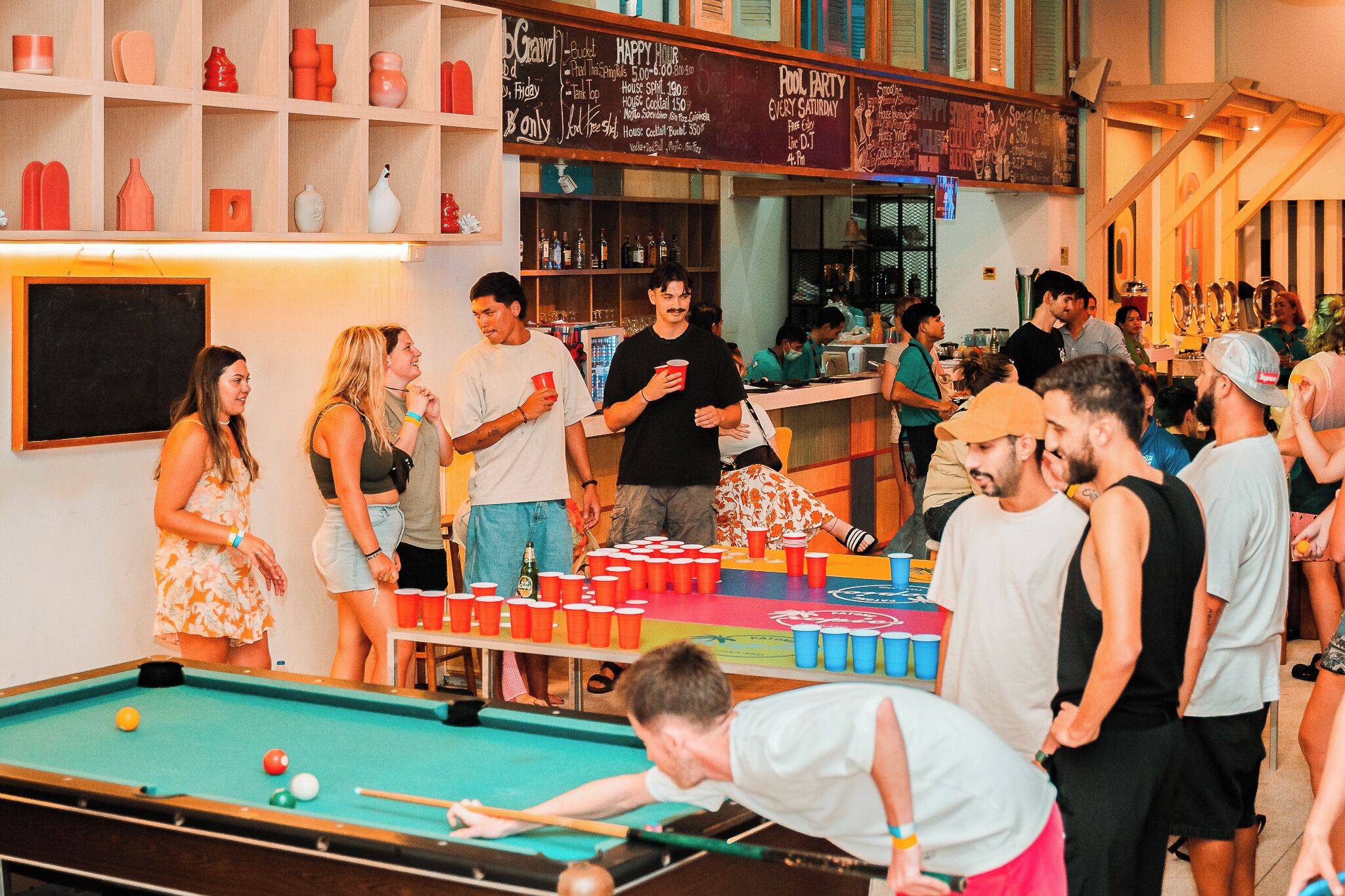 A pool table in a social setting with people around.