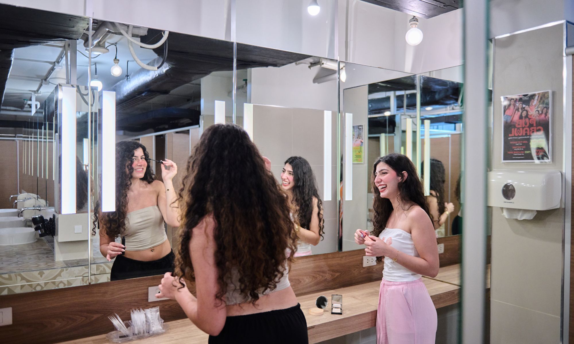 A modern bathroom with a large mirror, a sink, and a vanity with toiletries.