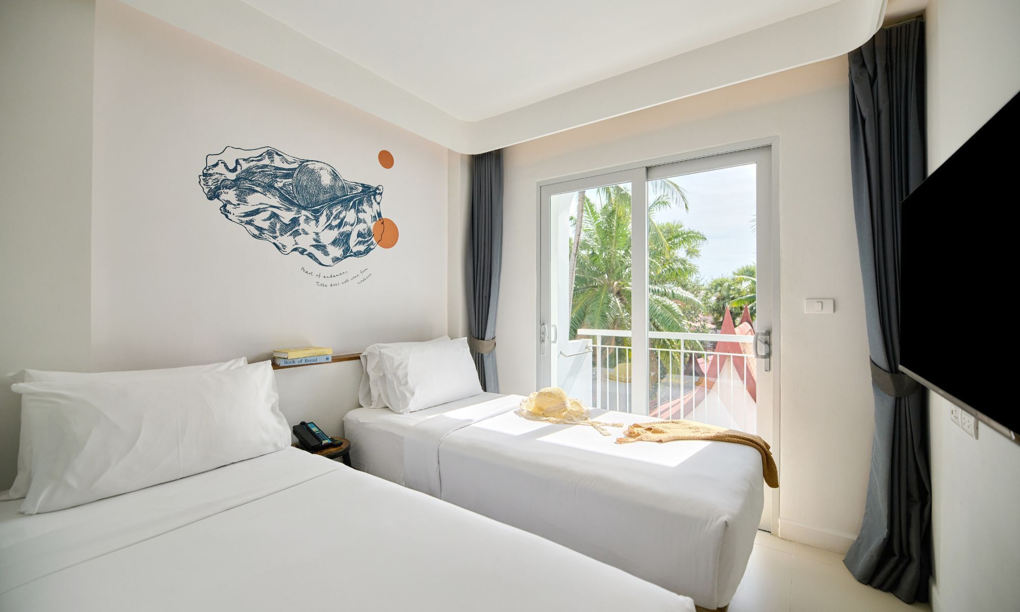 Quarto de hotel com duas camas, uma janela grande e um adorno na parede.
