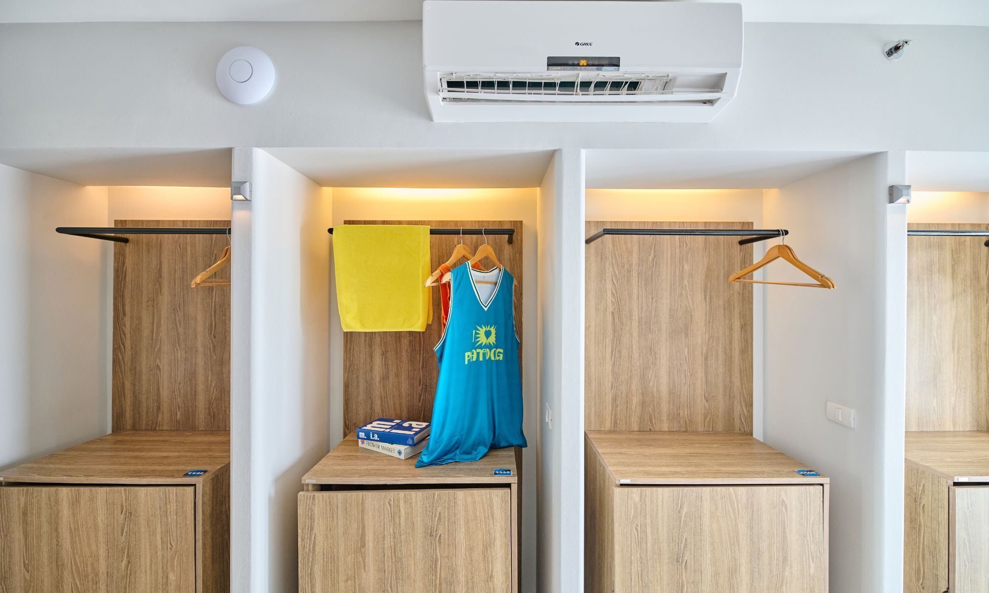 A hotel room with a central wardrobe, a hanging garment, and a small table with a box.