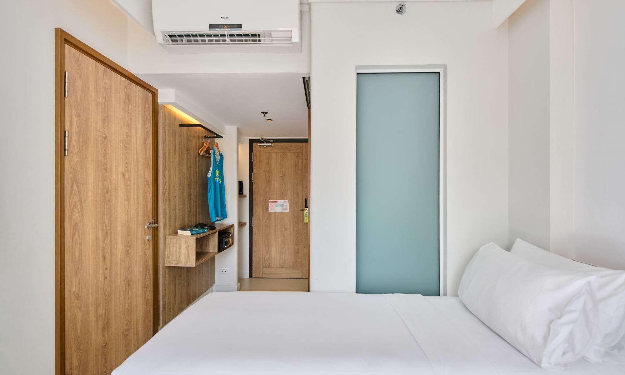 A bedroom with a bed, a wardrobe, a mirror, and an air conditioning unit.