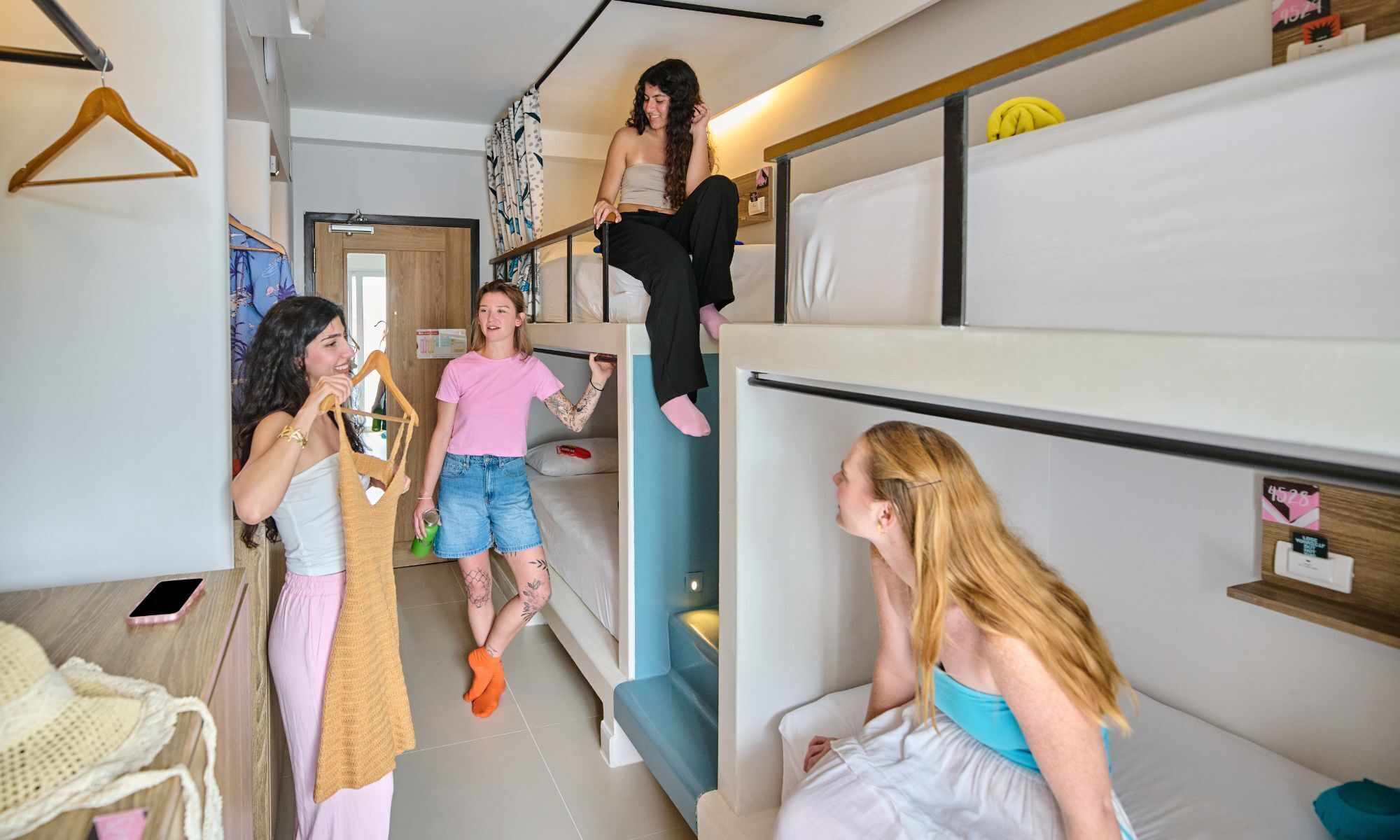 A dormitory room with bunk beds, a desk, and a chair.