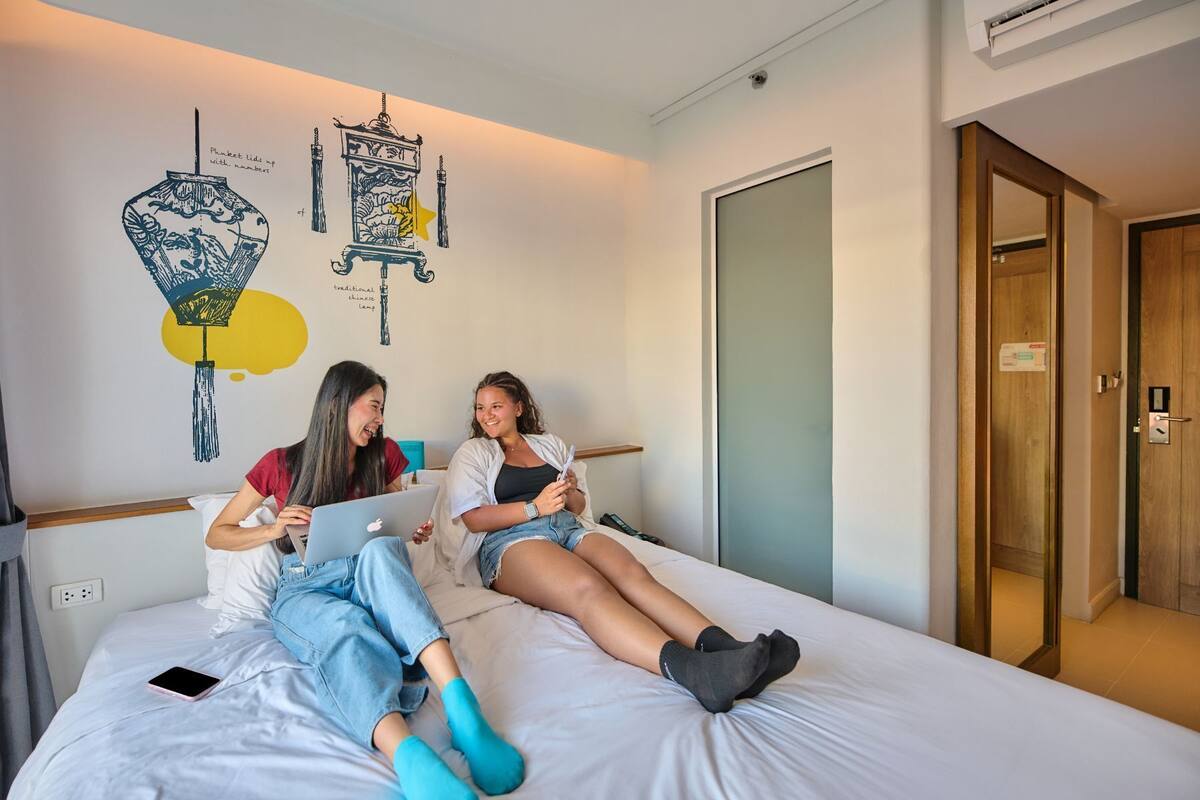 A bedroom with a bed, a wall with decorative elements, and a door.
