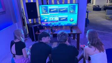 Un grupo de personas sentadas frente a una pantalla grande que muestra la interfaz de un videojuego.