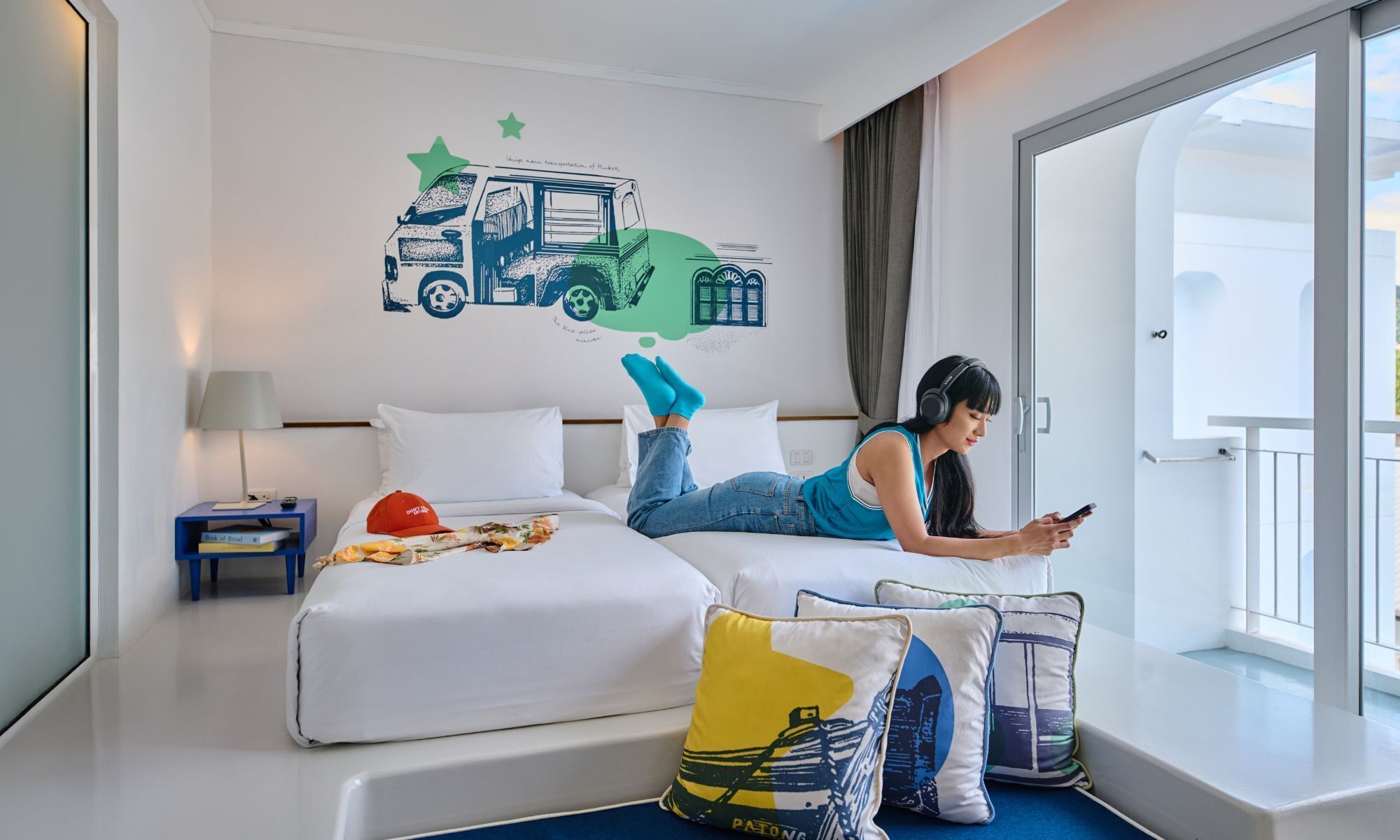 A hotel room with a bed, a nightstand, a window with curtains, and a wall decoration of a truck.