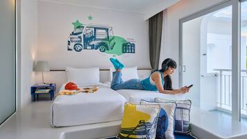 Habitación de hotel con cama, mesita de noche, ventana con cortinas y una decoración de camión en la pared.