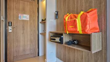 Habitación de hotel con puerta de madera, estante con una bolsa Lubb, un termostato y un pequeño objeto decorativo.