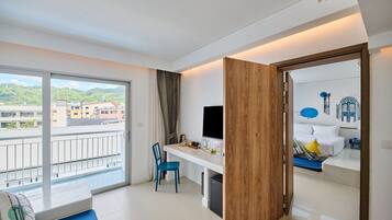 Ein Hotelzimmer mit Balkon, Schreibtisch mit Stuhl, Bett und Fernseher.