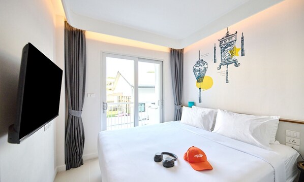 A hotel room with a bed, a TV mounted on the wall, and a window with curtains.