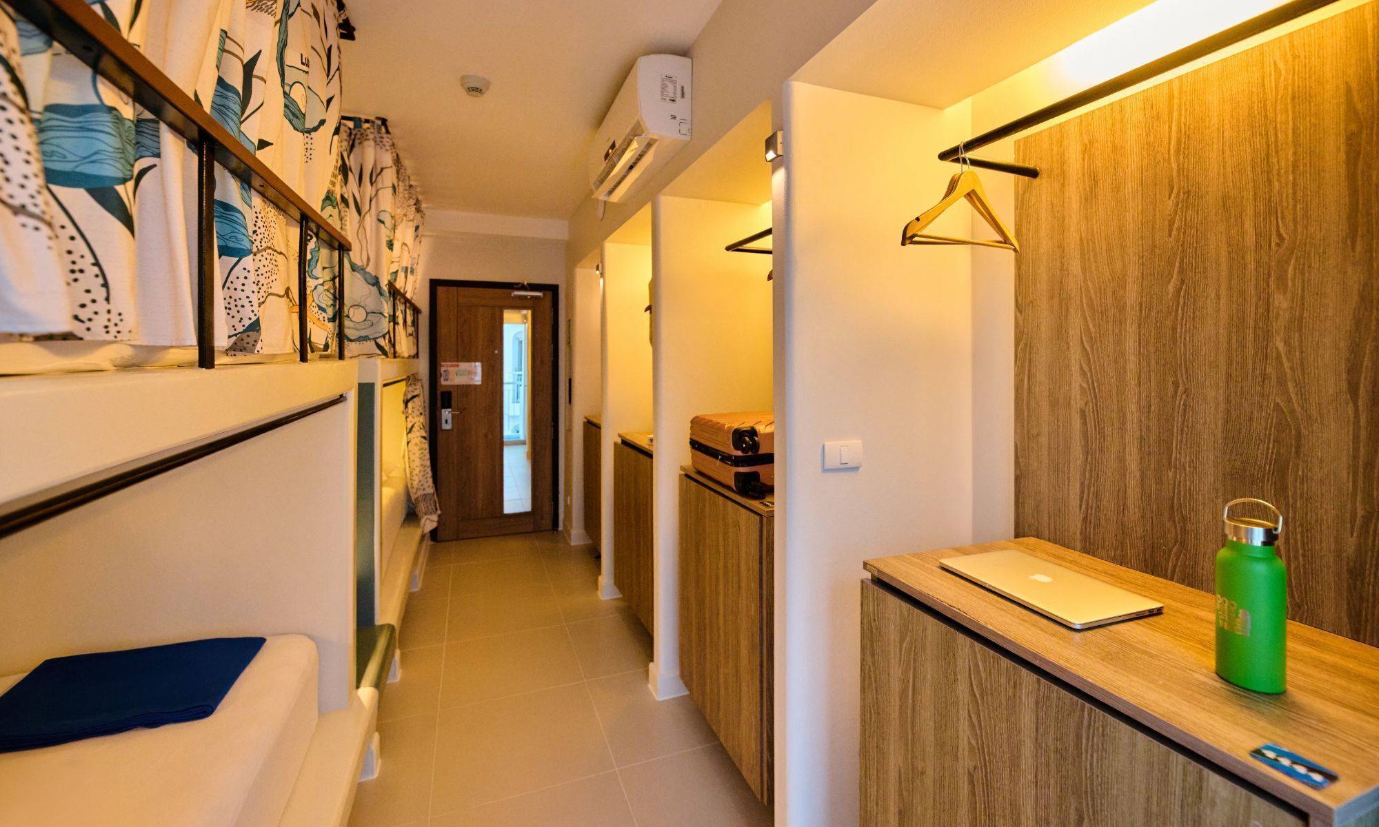 Un pasillo de hotel con un mostrador de recepción de madera, un perchero y una maleta sobre un mueble.