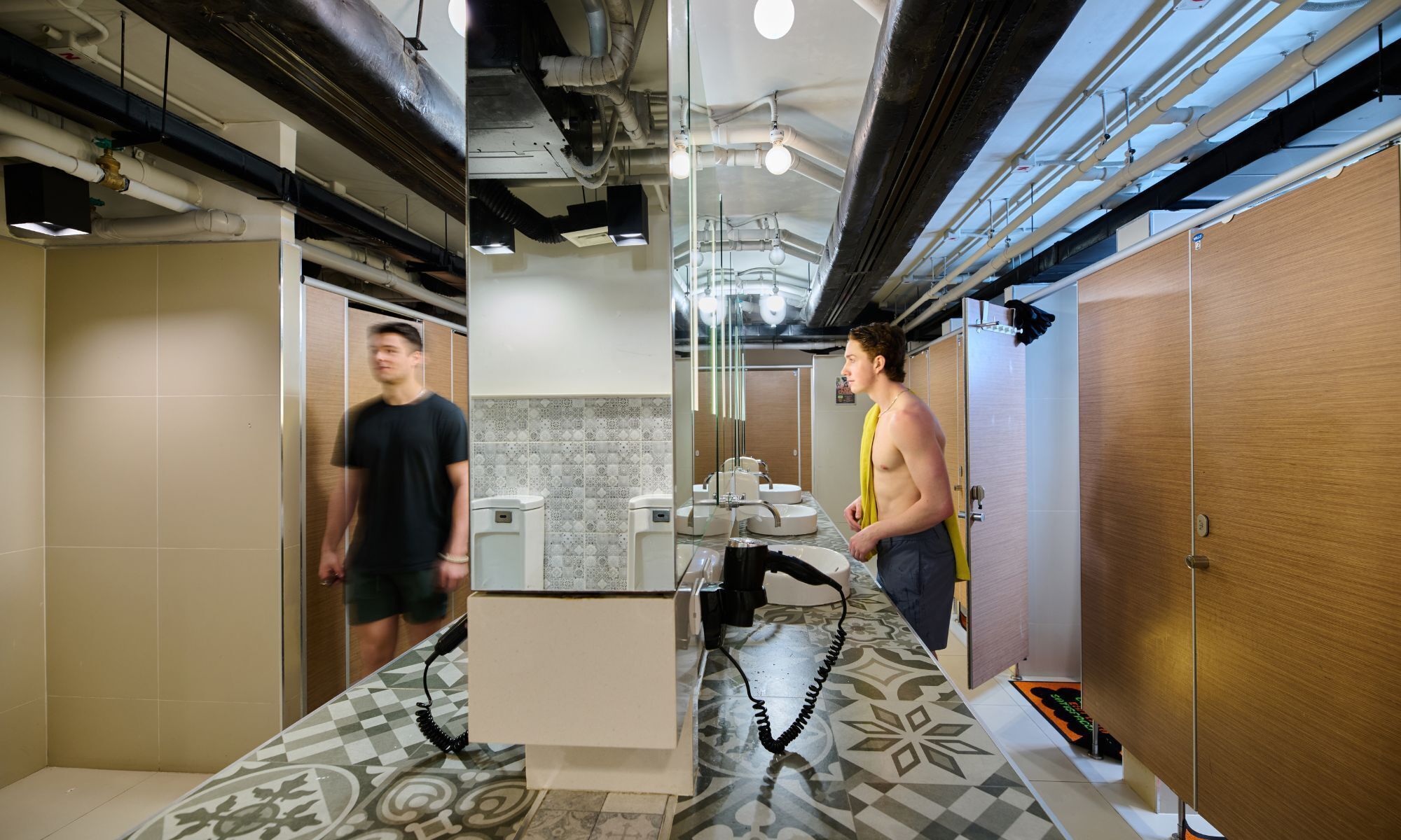 A modern restroom with patterned floor tiles, a central sink, and a mirror.