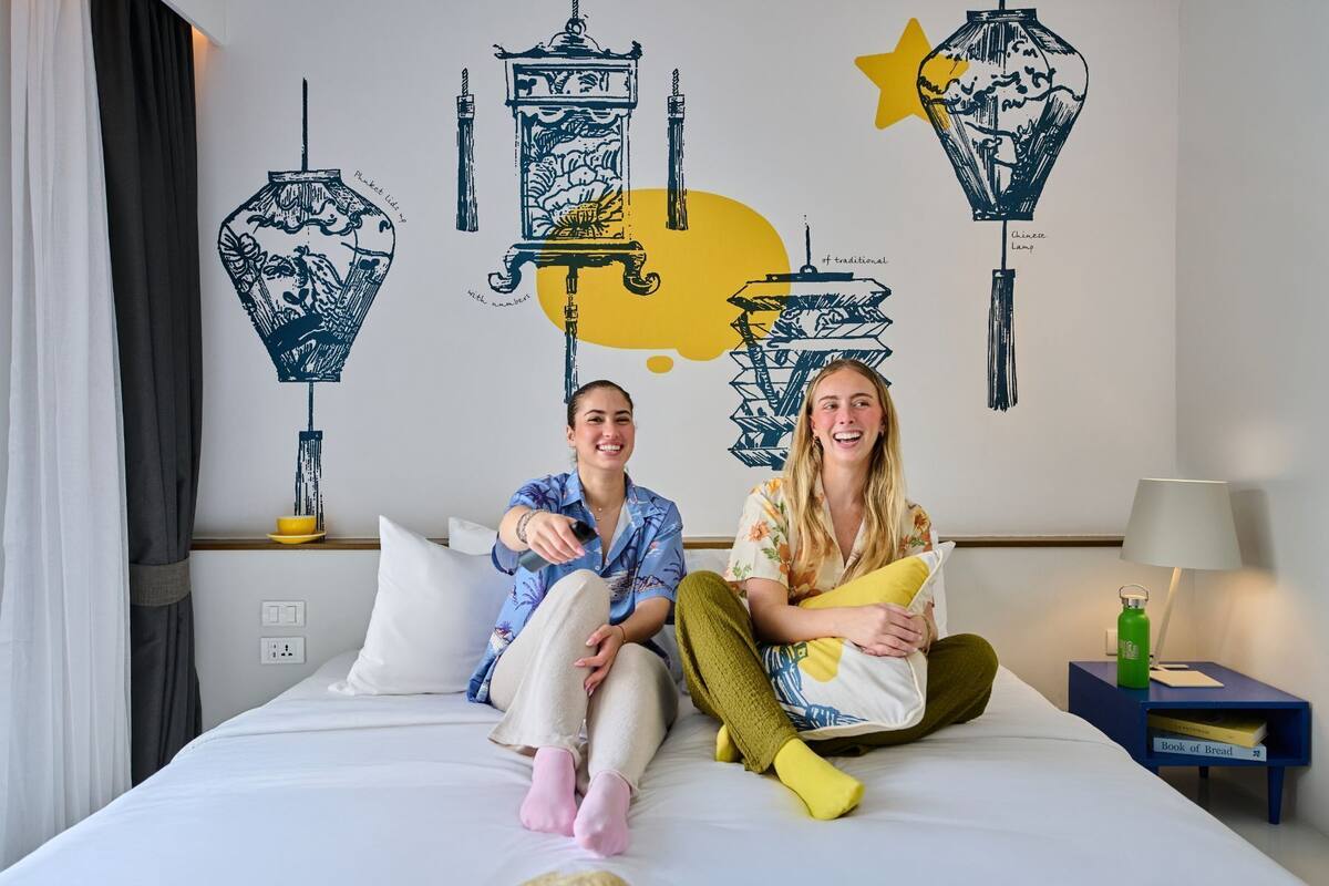 A hotel room with a bed, a nightstand with a lamp, and a wall with decorative wall art.