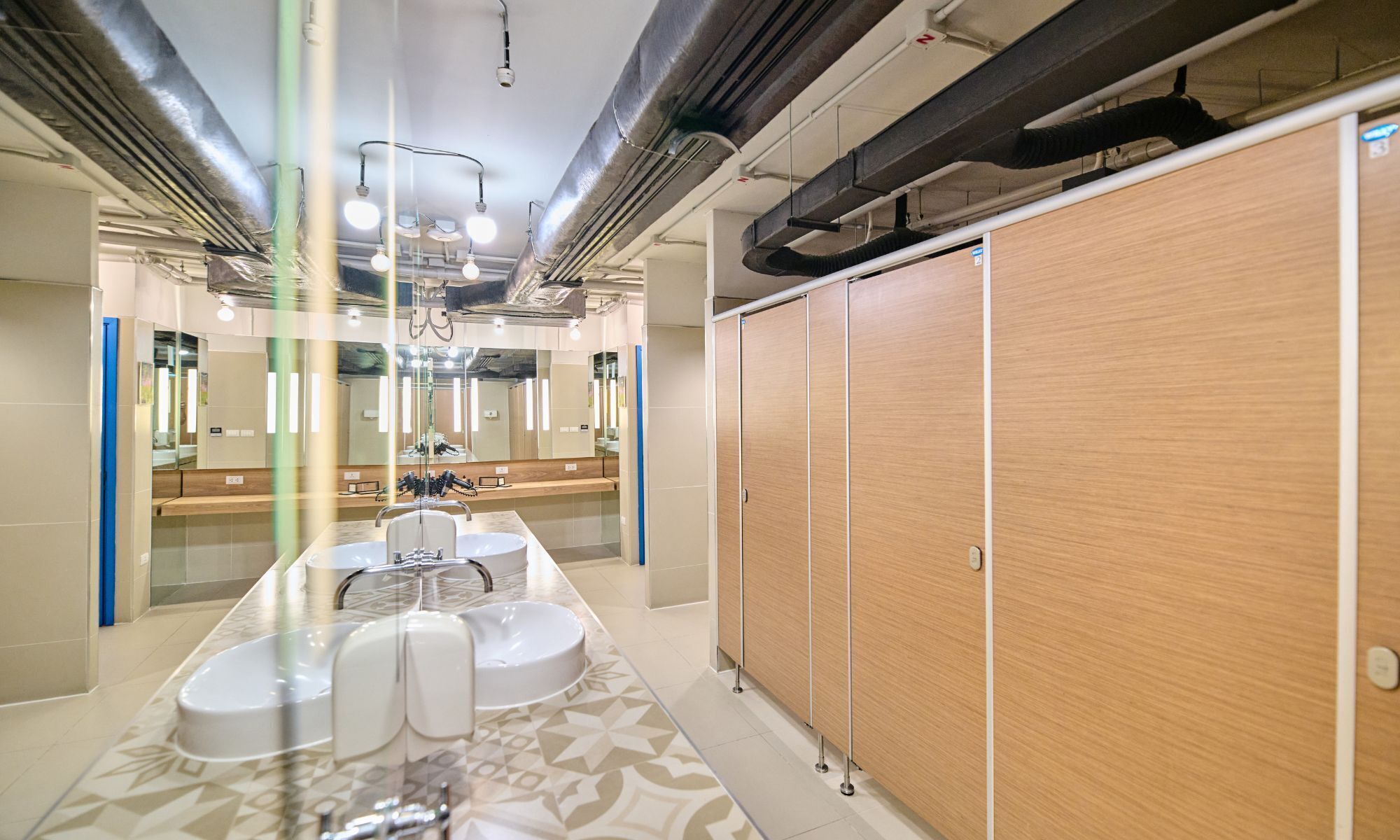 Un baño moderno con zona de lavamanos central, espejos y armarios de madera.