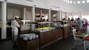 A buffet area with multiple serving stations, a chef, and guests dining. - Eden Club Skanes (Monastir)
