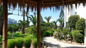 A covered outdoor area with a pathway lined by rocks and greenery, leading to a building with circular windows and a white exterior. - Eden Club Skanes (Monastir)