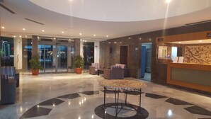 A lobby with a reception desk, seating area, and a glass door entrance. - Eden Club Skanes (Monastir)