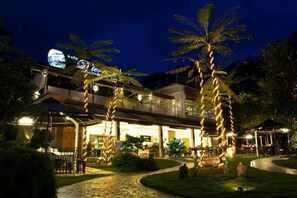 A hotel with a covered outdoor area, palm trees, and a sign that reads "Gunn's Cafe." - Laman Pesona Resort & Spa (Raub)