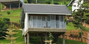 Una casa de dos pisos con balcón, rodeada de vegetación.