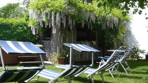 A patio with striped lounge chairs, a small table, and a wooden cabinet. - Garni Meinrad (Ora)