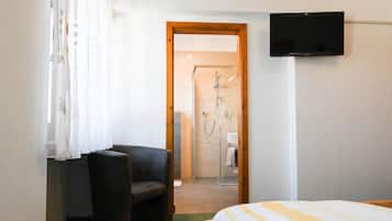 Ein Hotelzimmer mit Bett, Stuhl, Fernseher und Duschbereich.