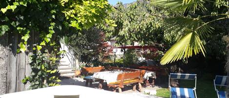 Un patio trasero con piscina, terraza de madera y mobiliario exterior.
